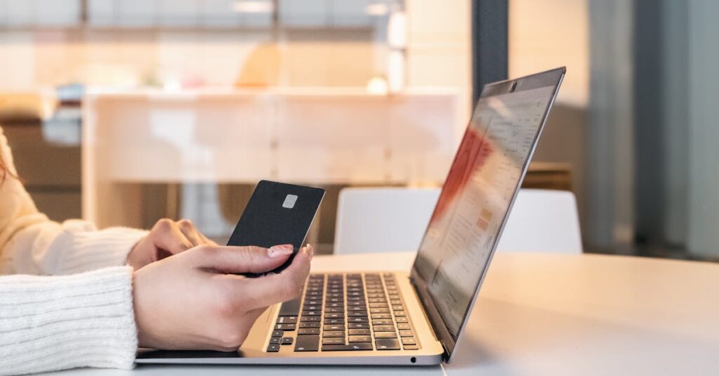 A woman using a credit card and laptop for online shopping in a modern indoor setting.